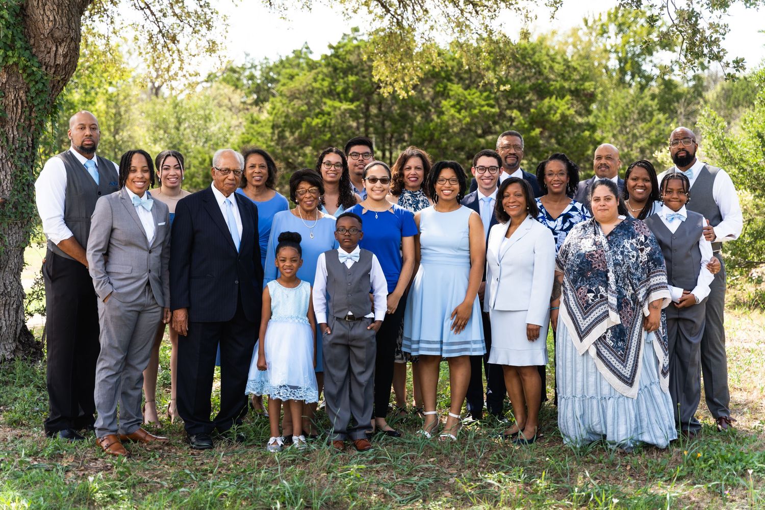 A multigenerational family gathering outside in coordinated blue and white outfits.