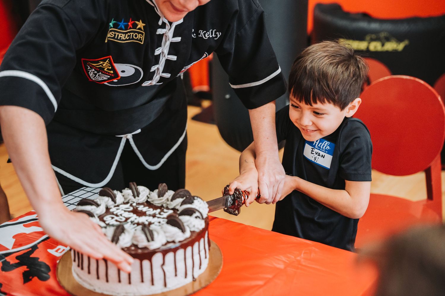 Chocolate birthday cake being served in martial arts studio with black and orange decor.