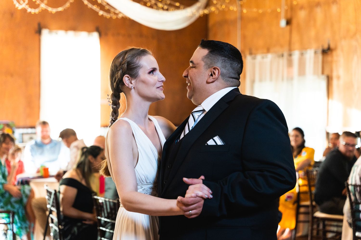 A couple shares their first dance in an elegantly decorated rustic reception venue.