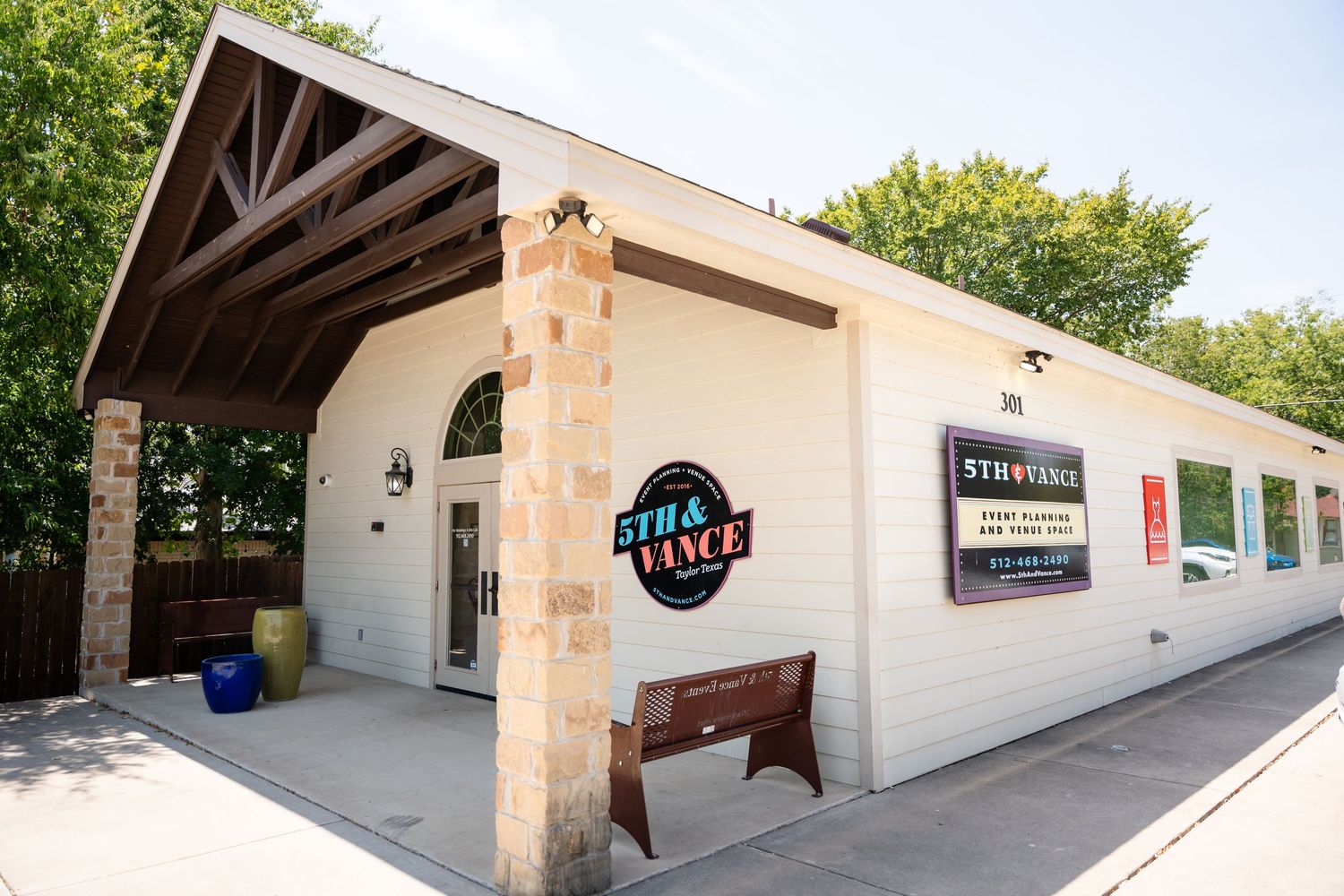White stucco building exterior with wooden beams and stone accents featuring business signage.