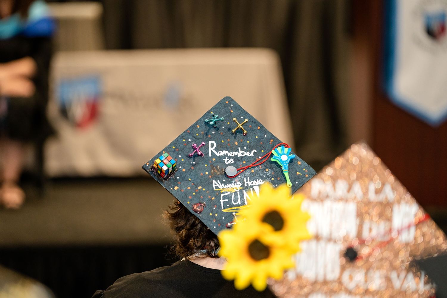 A graduation cap with a sunflower decoration visible from the side during commencement.