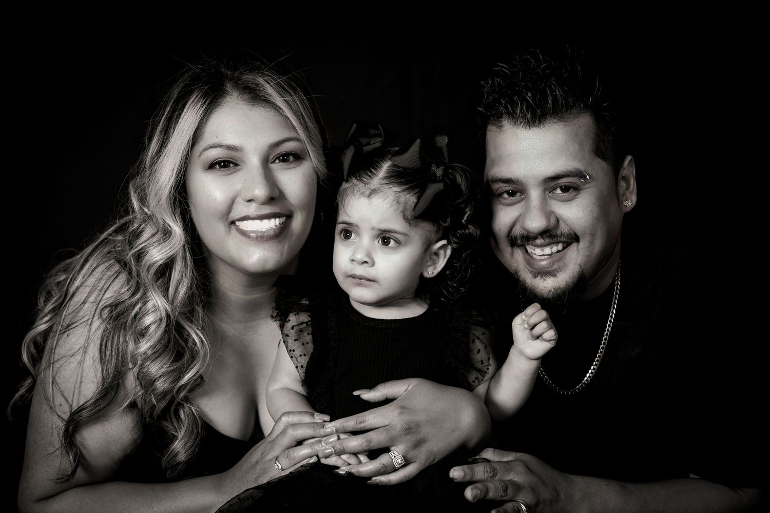 Classic black and white family studio portrait showing warmth and connection against dark background.