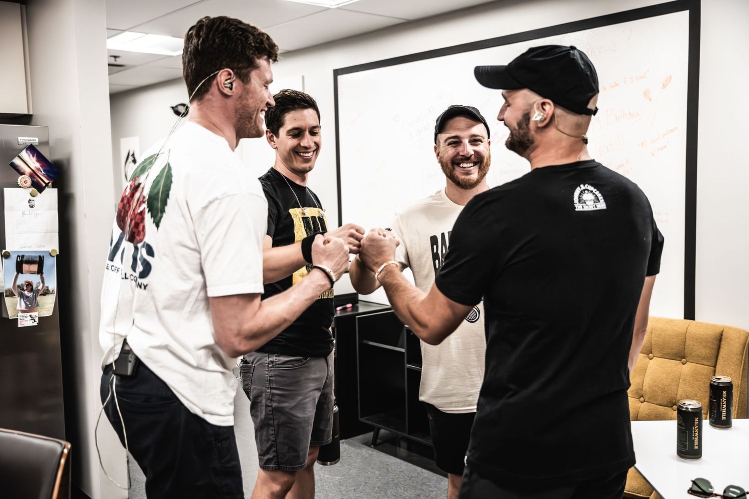 Musicians sharing a celebratory handshake in a rehearsal room.