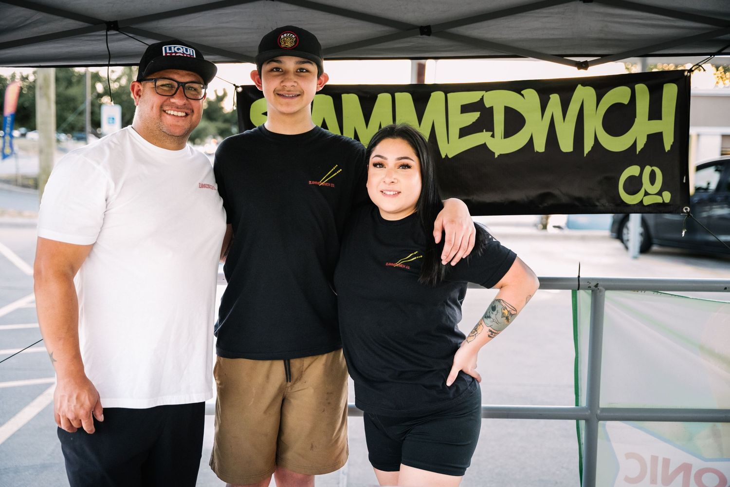 Staff members standing together under the Slammedwch Co. banner at an outdoor event.