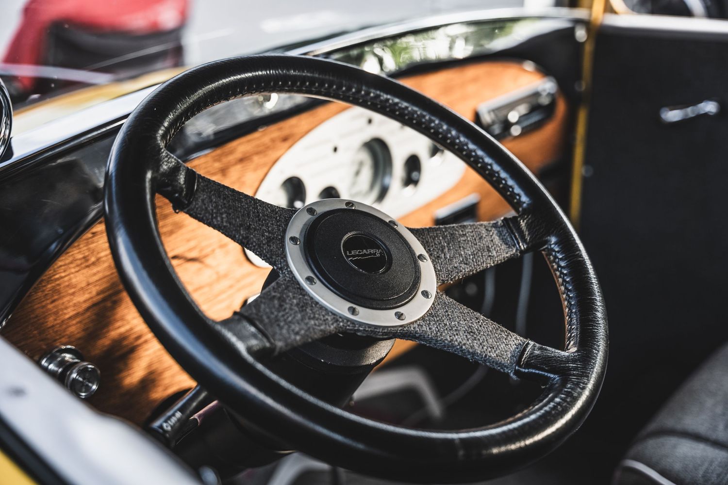 Vintage wooden steering wheel and dashboard detail in classic car interior.