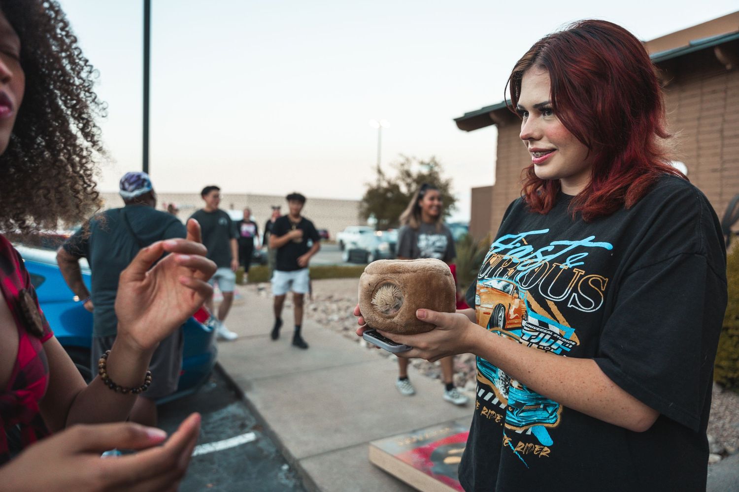 Car enthusiasts gather at a parking lot meetup showing off their custom vehicles.