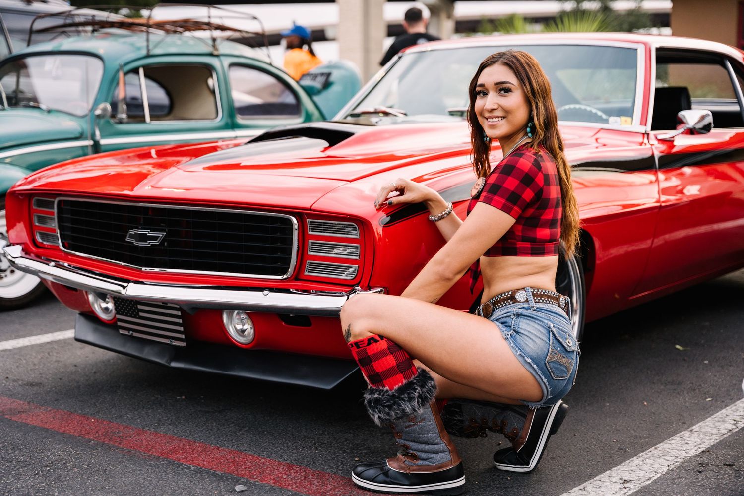 Classic red Chevrolet Camaro displayed at outdoor car show.