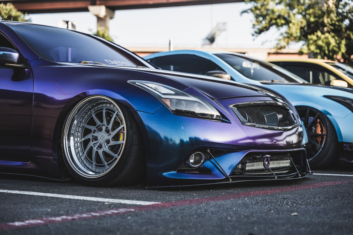 Purple and blue color-shifting modified sports car showcasing aggressive stance and custom wheels.