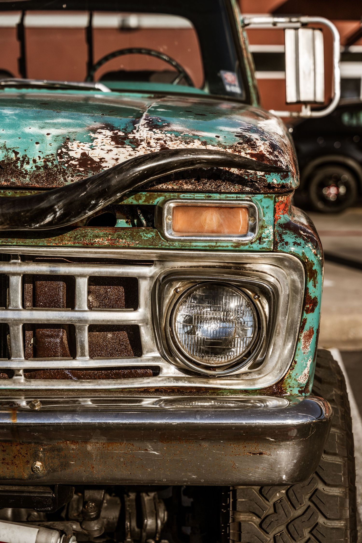 Close up of rusty turquoise vintage Ford truck headlight and grille.