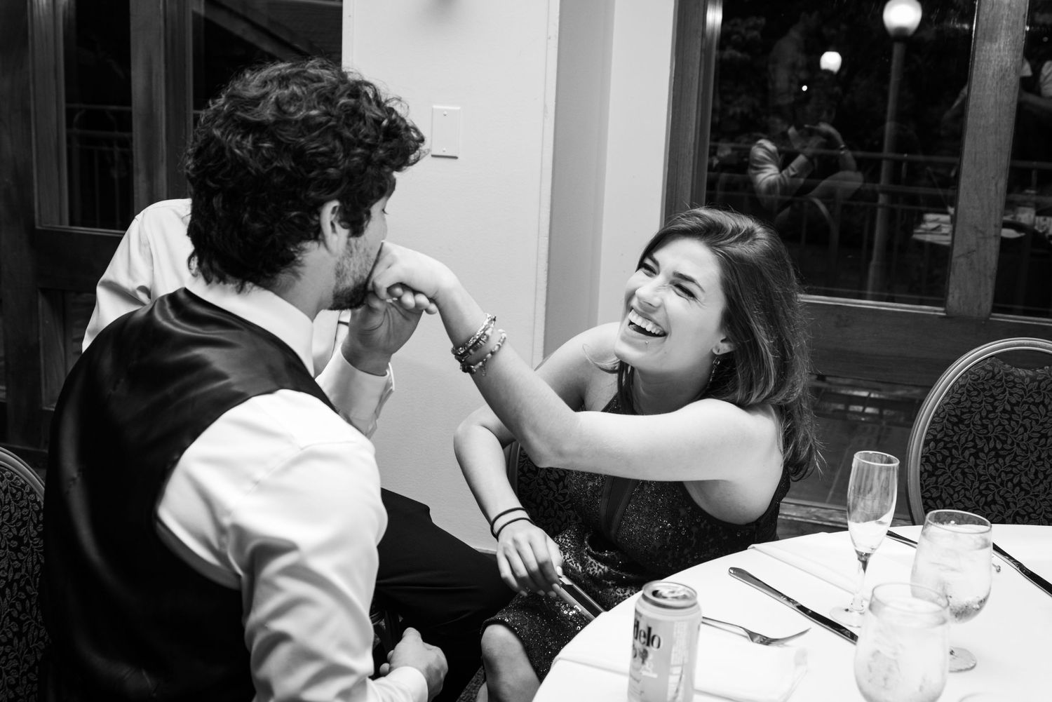 A candid black and white photo of guests laughing during the wedding reception.