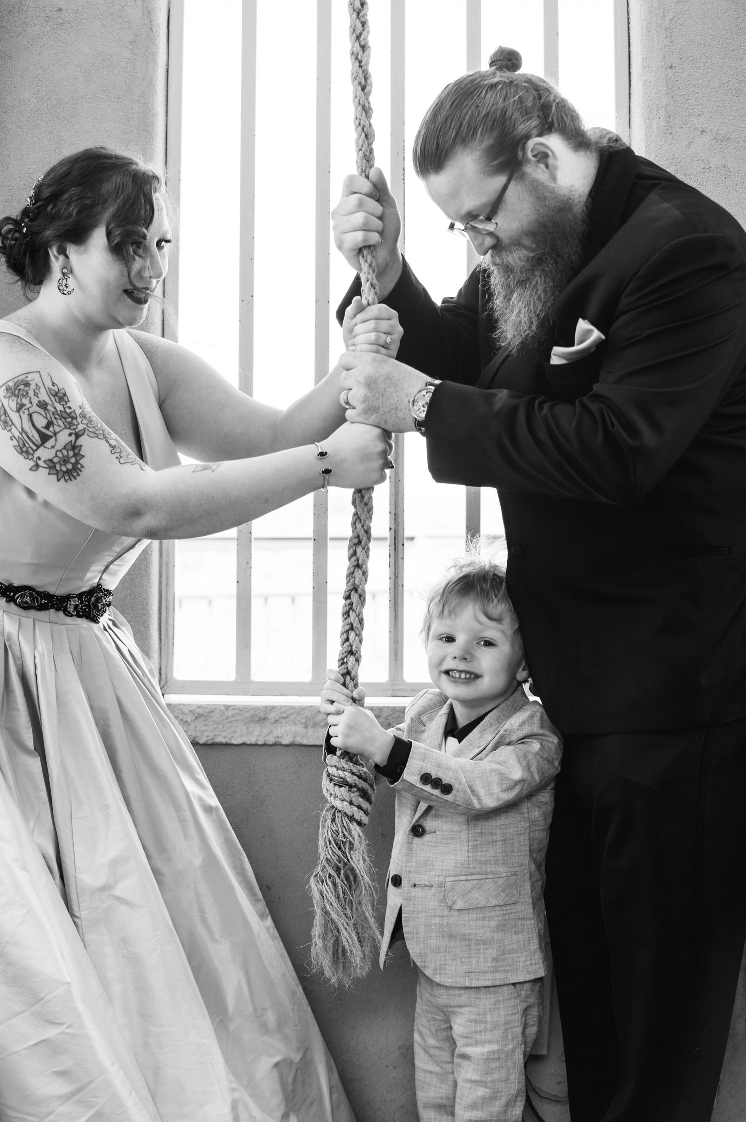 Black and white photo of a couple and child playfully tugging on a rope together.
