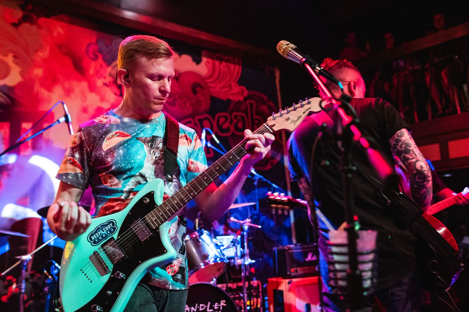 A guitarist playing on stage with red lighting and smoke effects.