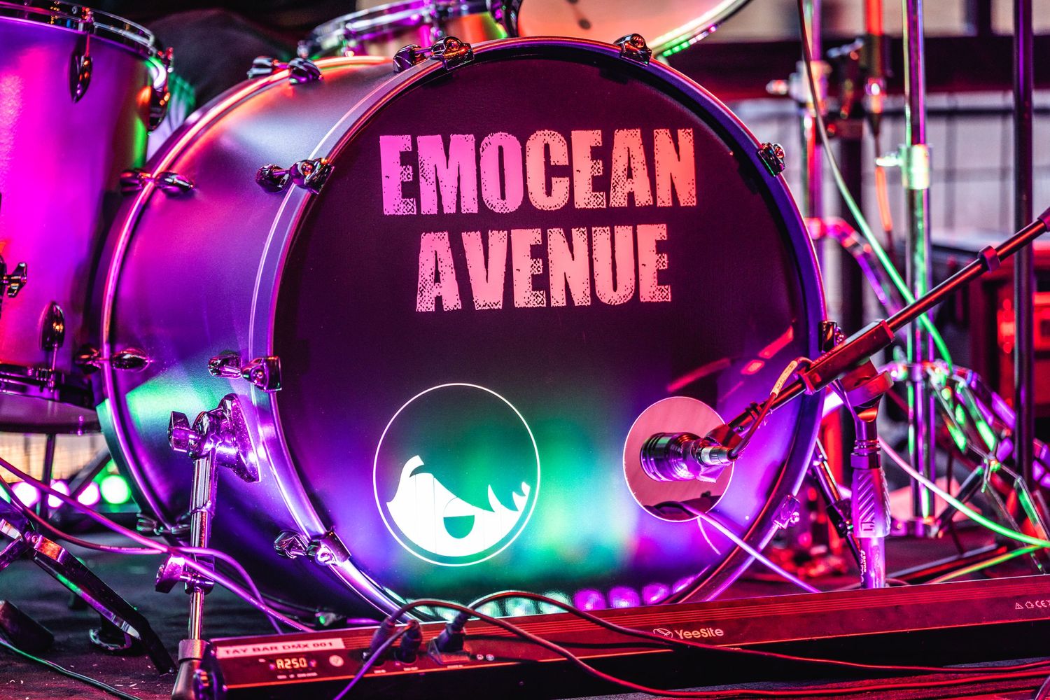 Illuminated bass drum with 'Emocean Avenue' text glowing in pink neon lights on stage.