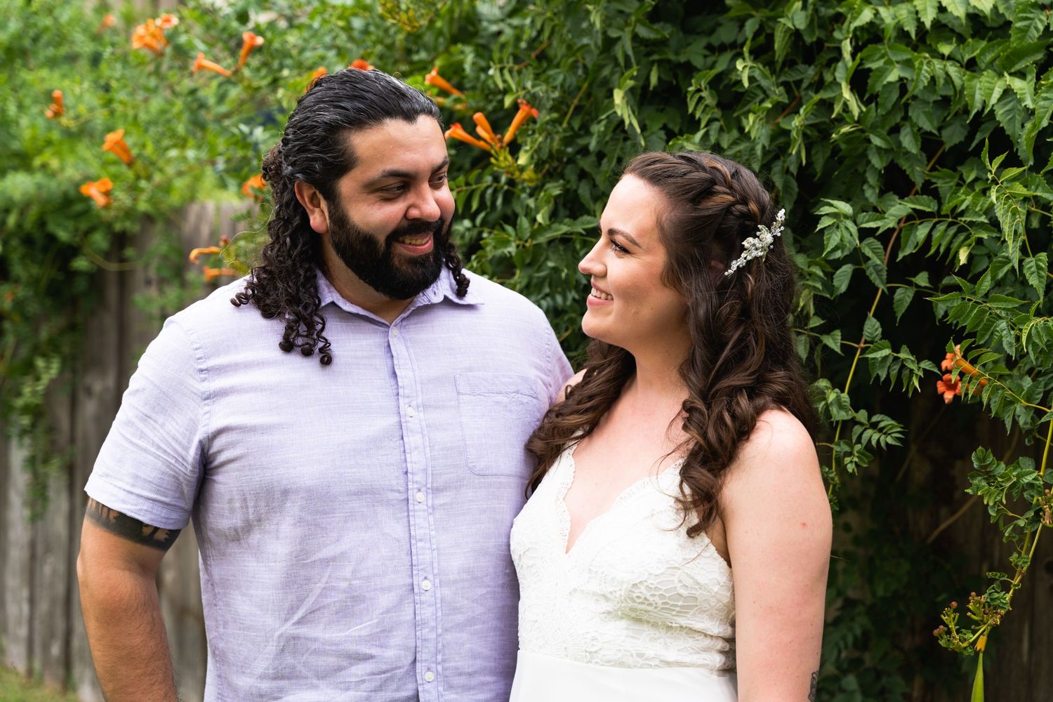 A couple shares a loving moment in a garden with orange flowers and greenery.