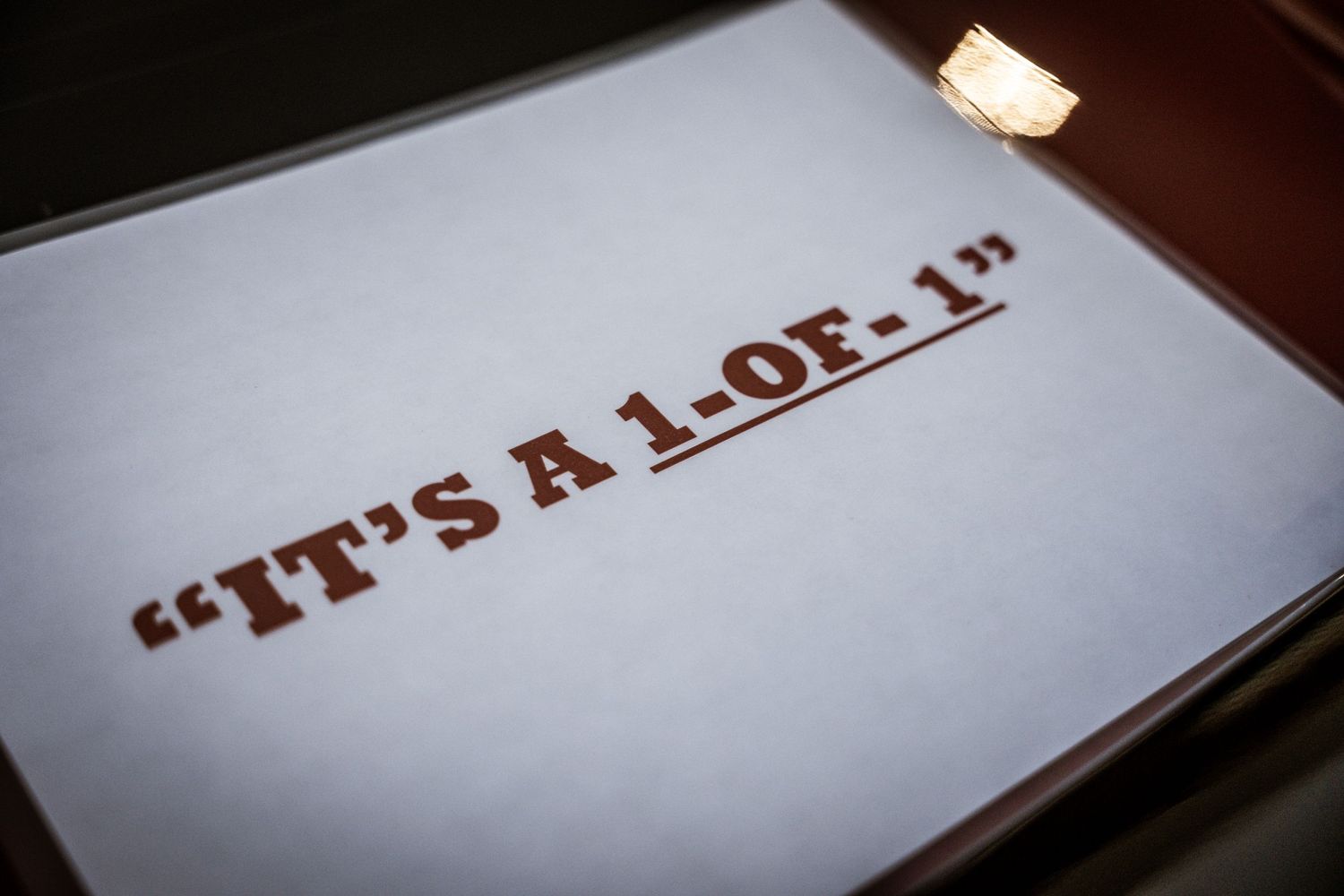 Close-up shot of text reading 'IT'S A 1.0E-11' on white paper under dim lighting.