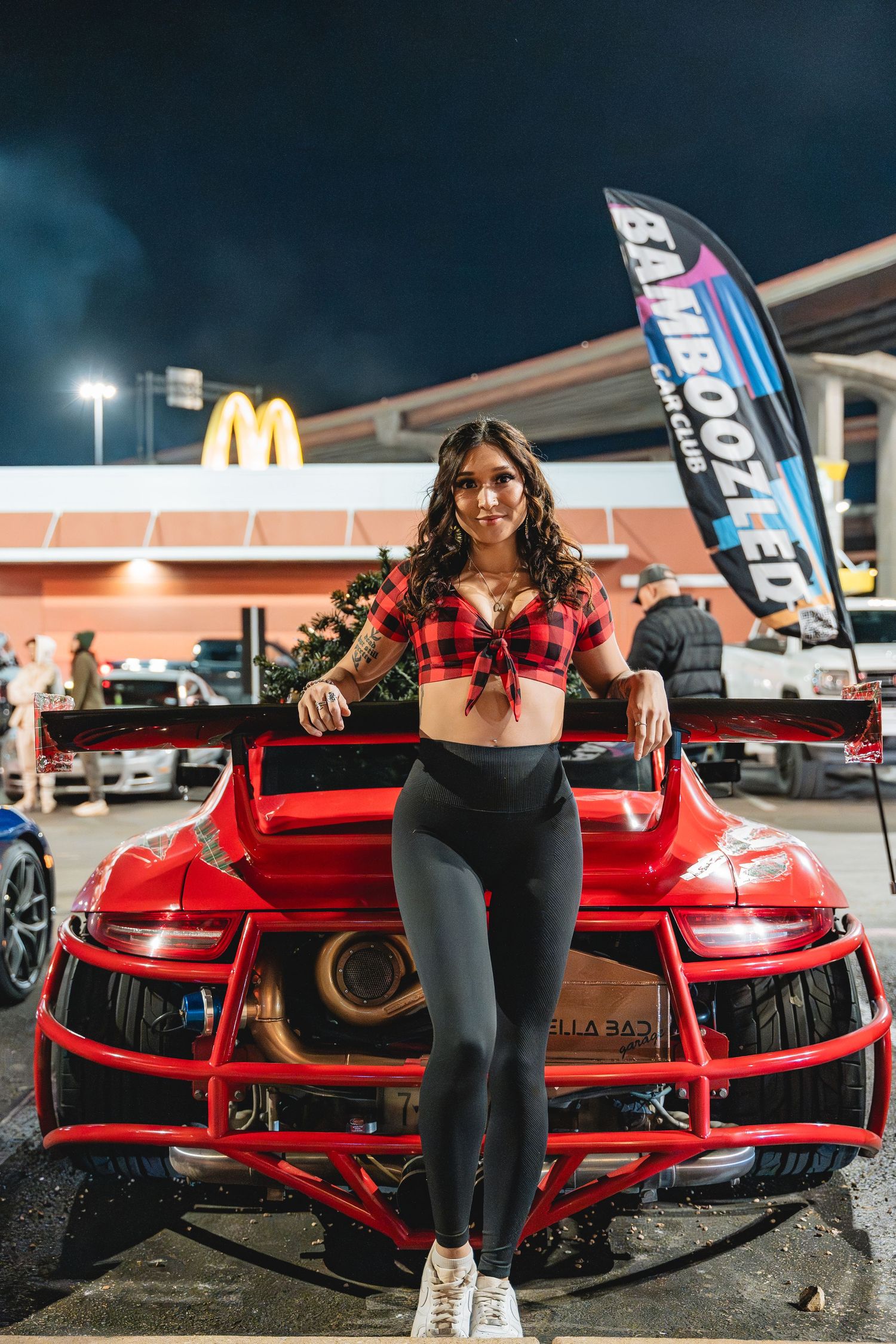 Someone poses with a red Porsche GT3 RS at night with McDonald's sign visible in background.