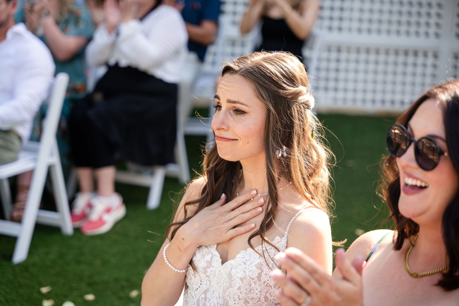 Candid emotional moment during outdoor wedding ceremony on green lawn with white chairs.