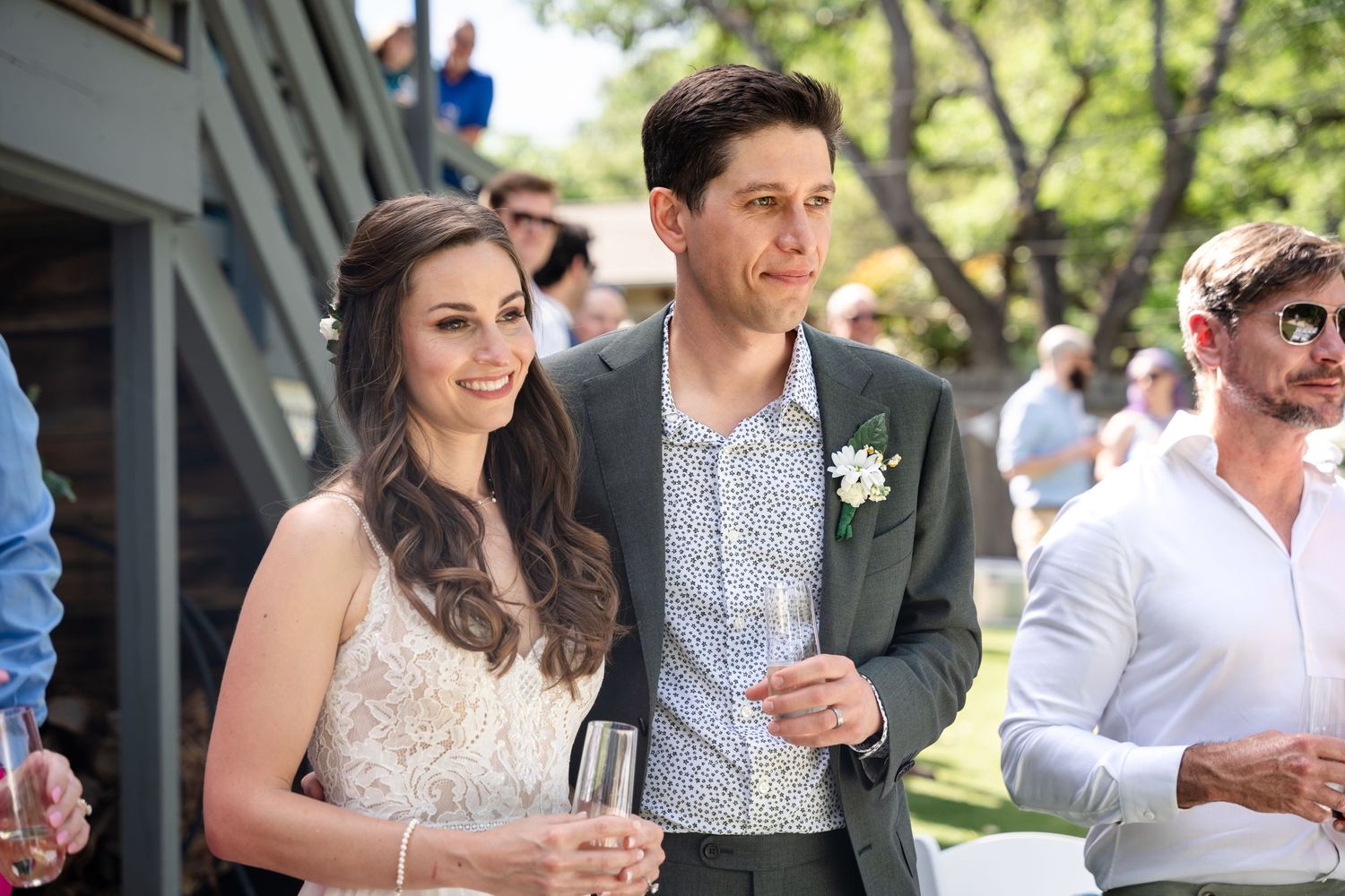 A couple enjoying drinks at an outdoor wedding reception.