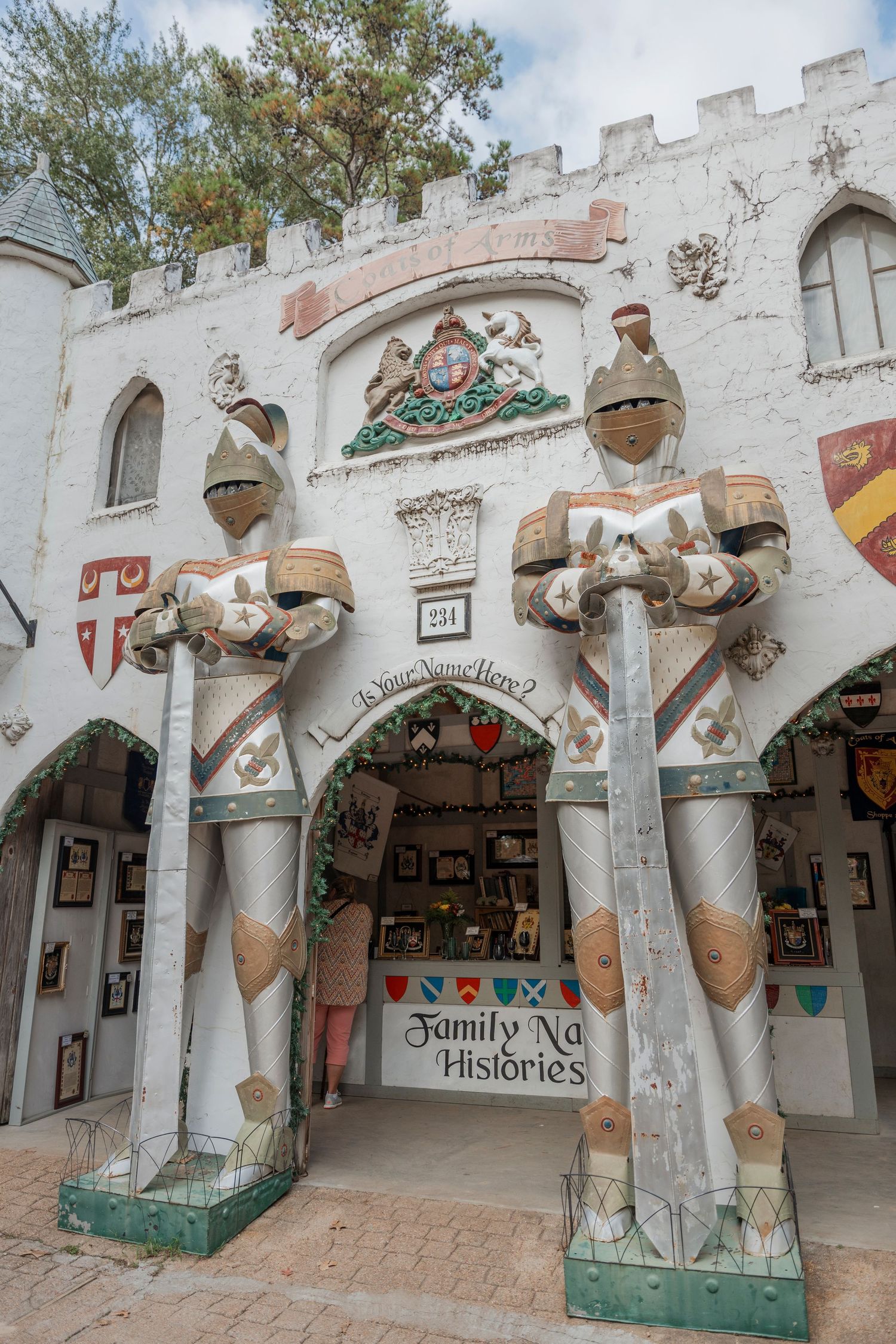 White castle entrance with decorative knight statues and family histories sign at renaissance faire.