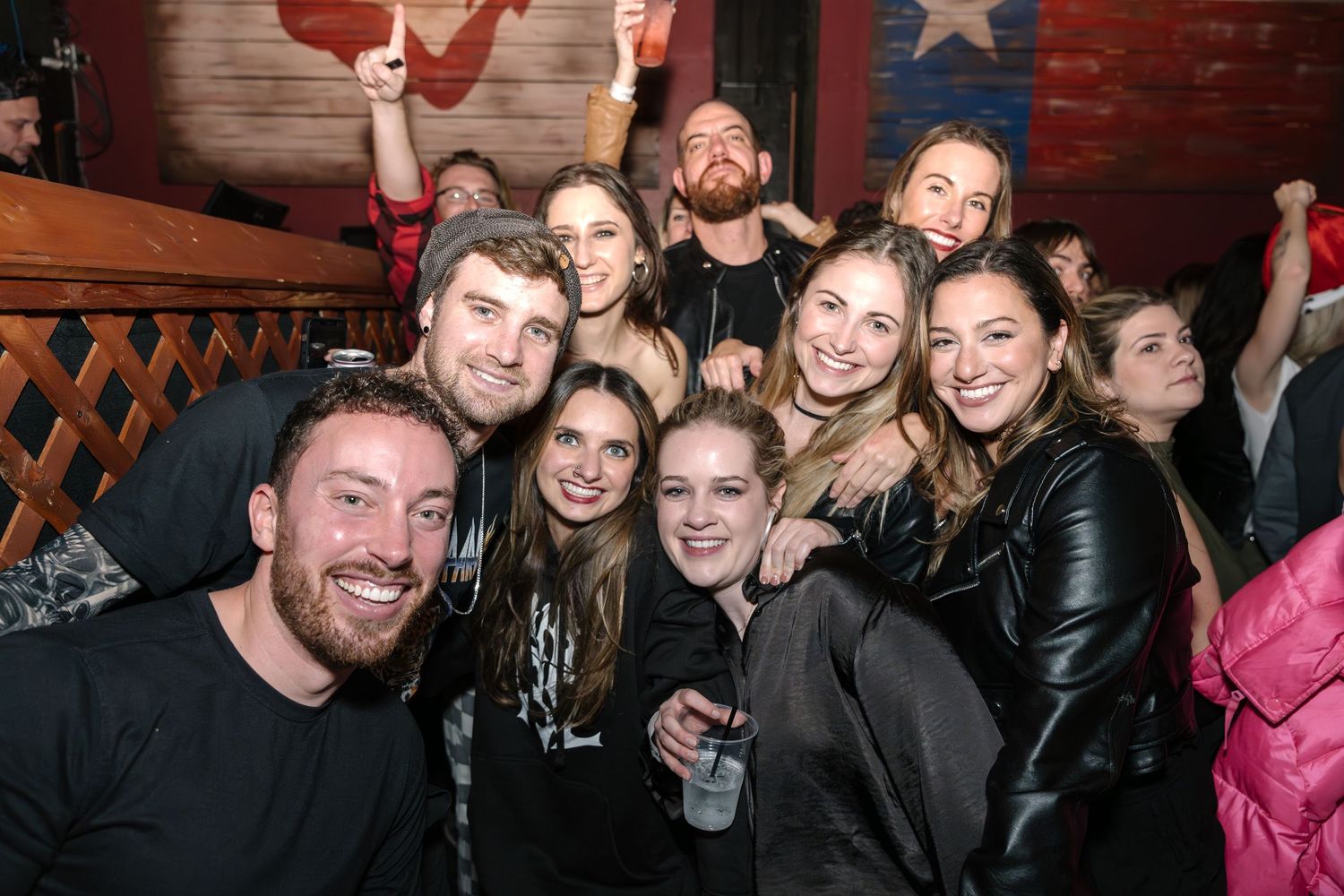 Concert attendees taking a group selfie at a music venue with decorative wall art.