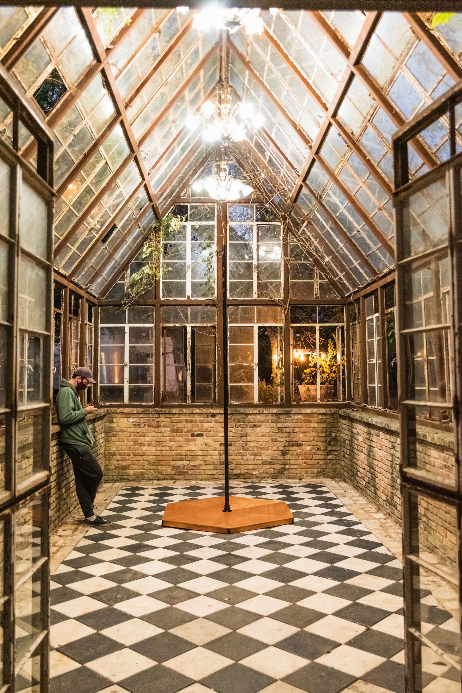 A greenhouse-style room with checkered floor, glass ceiling, and pole in the center.
