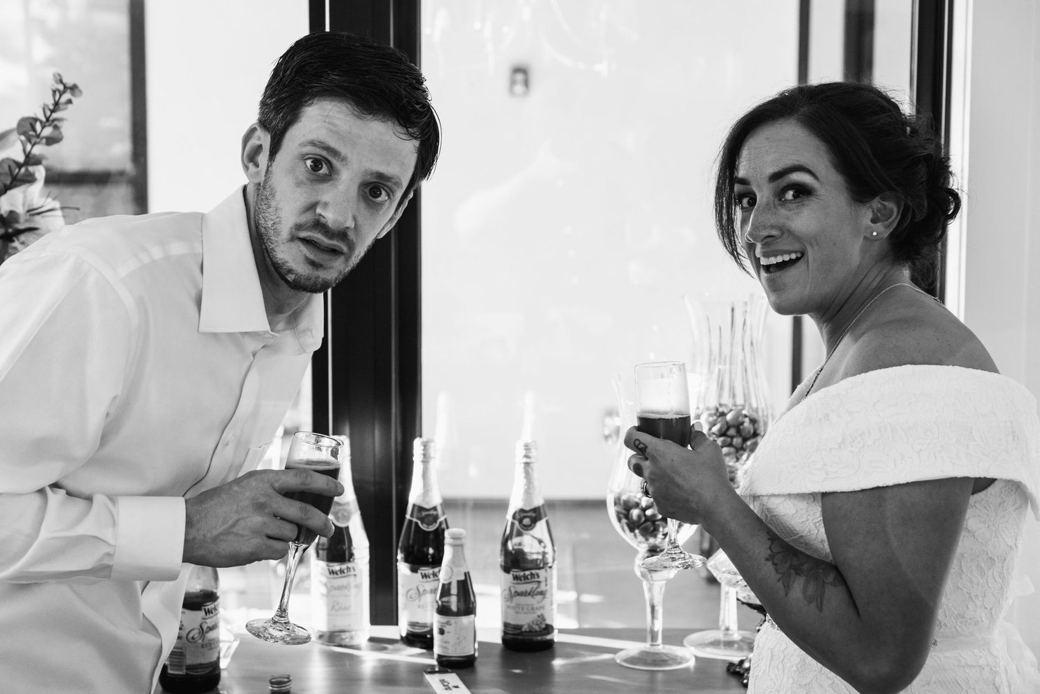 Two wedding guests share drinks and laughs at an indoor reception.
