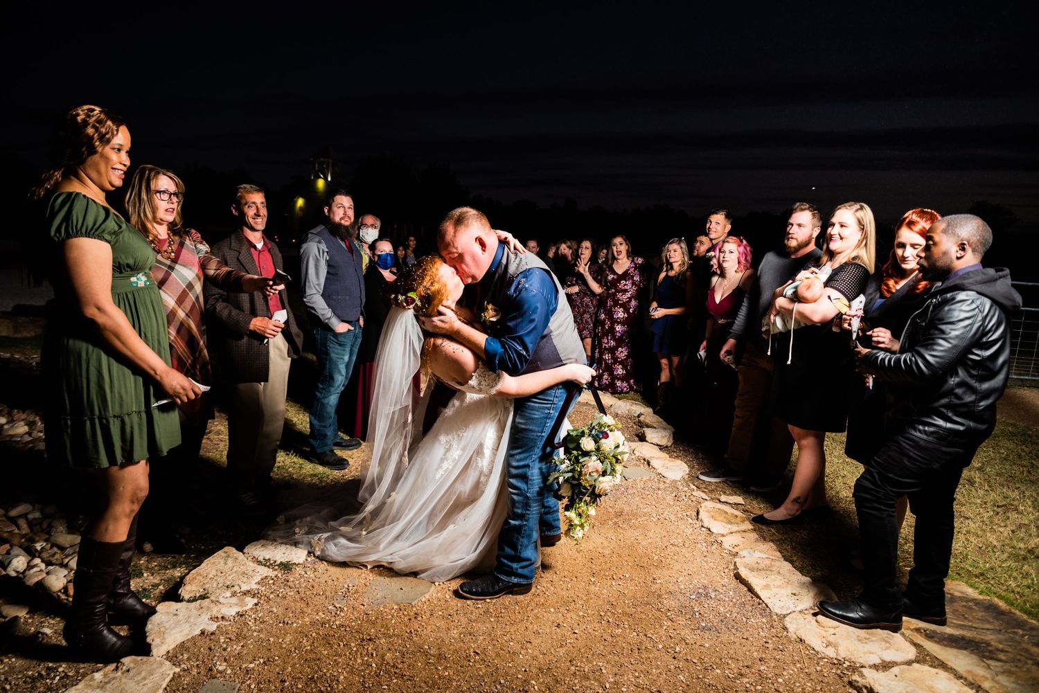 A nighttime wedding ceremony with guests holding lights surrounding the couple.