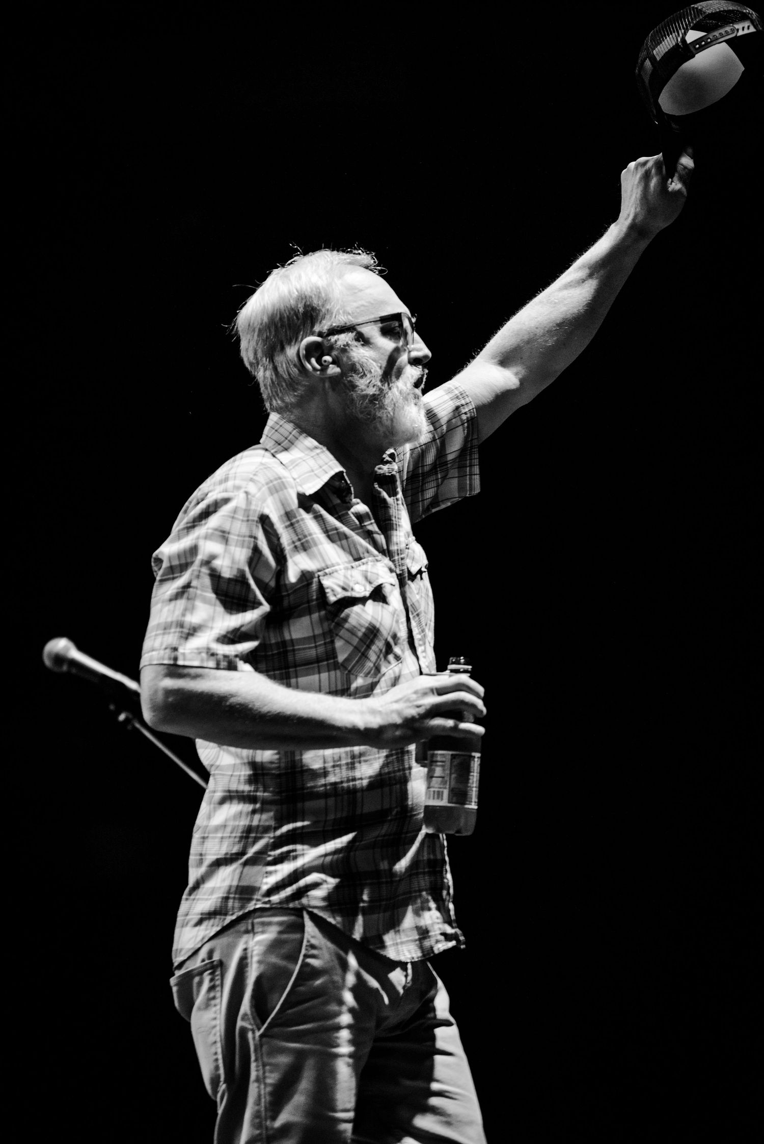 Black and white photo of performer raising an object overhead during an energetic stage performance.