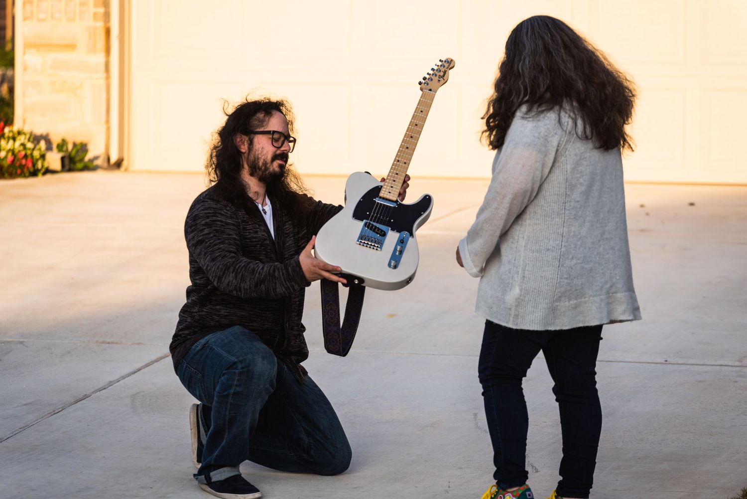 An outdoor proposal scene featuring an electric guitar and two people on a sidewalk.