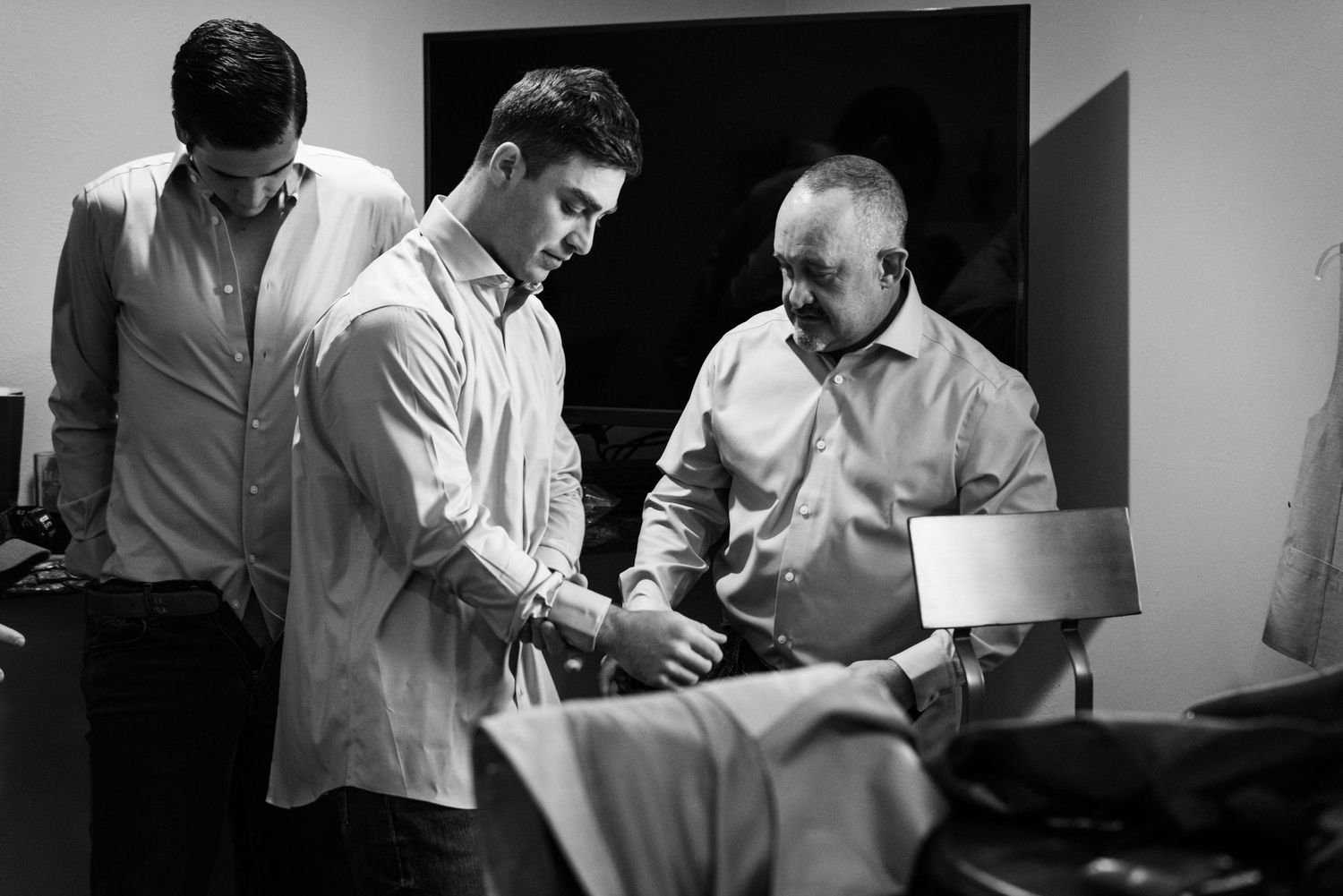 Black and white image of three people examining formal attire.