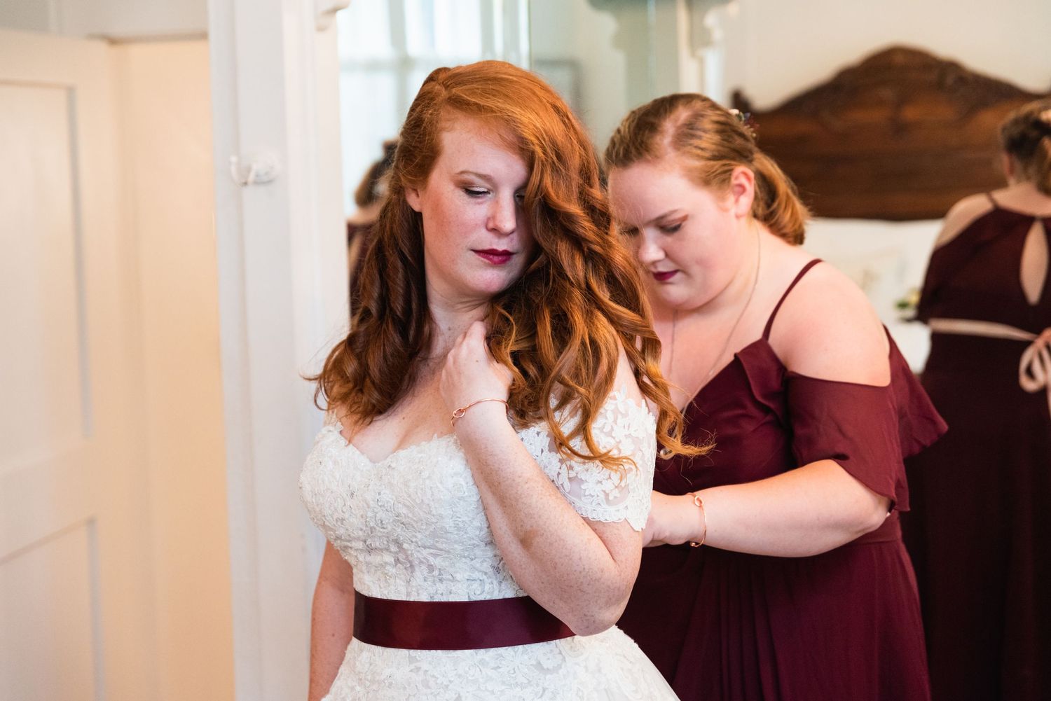 Getting ready scene with wedding dress and burgundy bridesmaid attire.