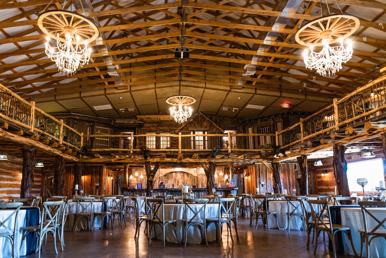 Elegant rustic reception hall with exposed wooden beams and ornate crystal chandeliers.