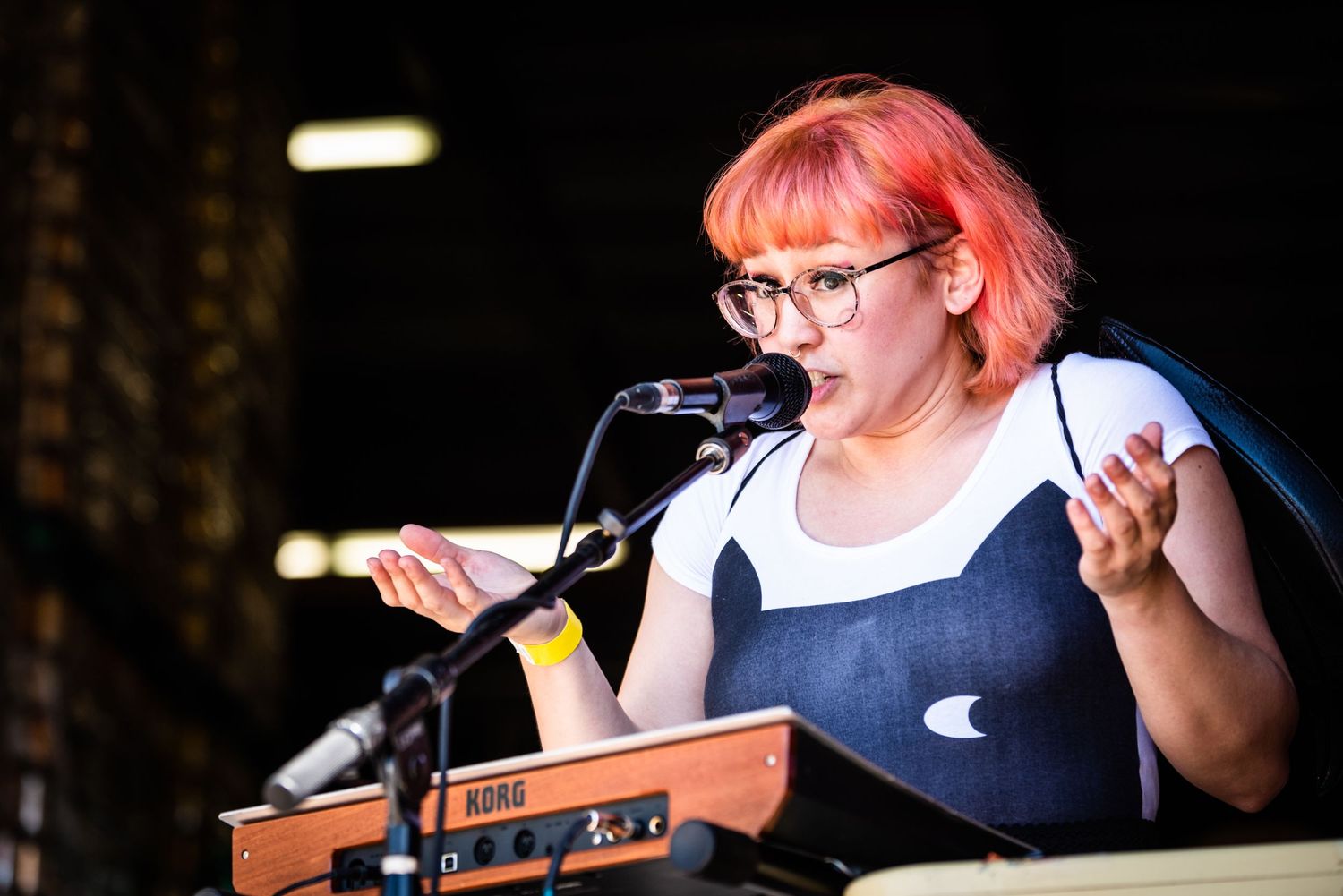 Performer plays keyboard and sings with expressive gestures during stage show.