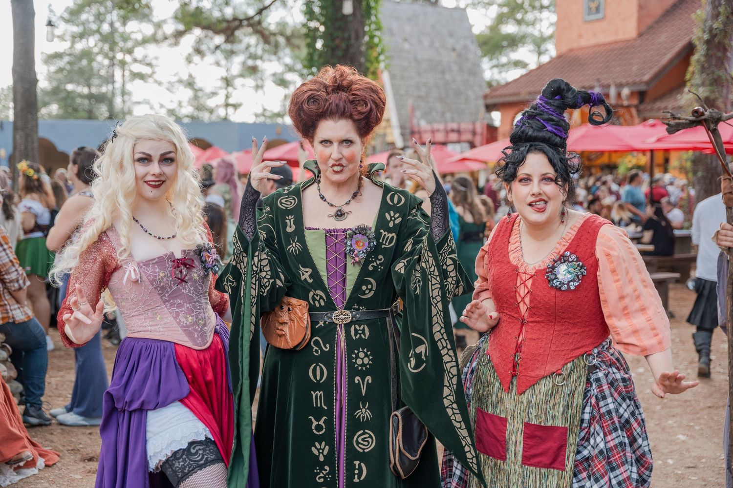 Group in elaborate Halloween costumes poses at outdoor festival.