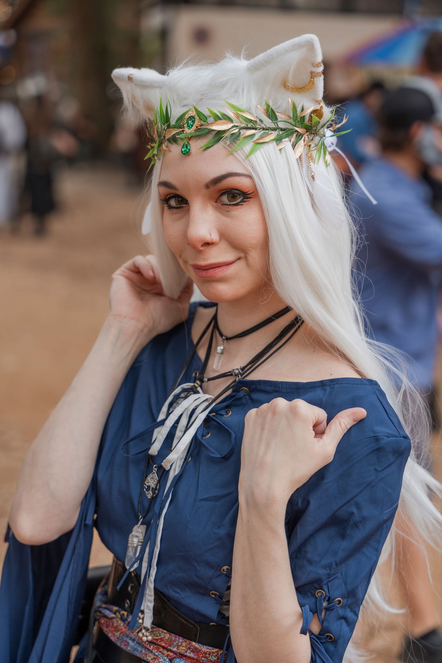 Costumed performer in blue medieval dress with floral crown at renaissance faire.