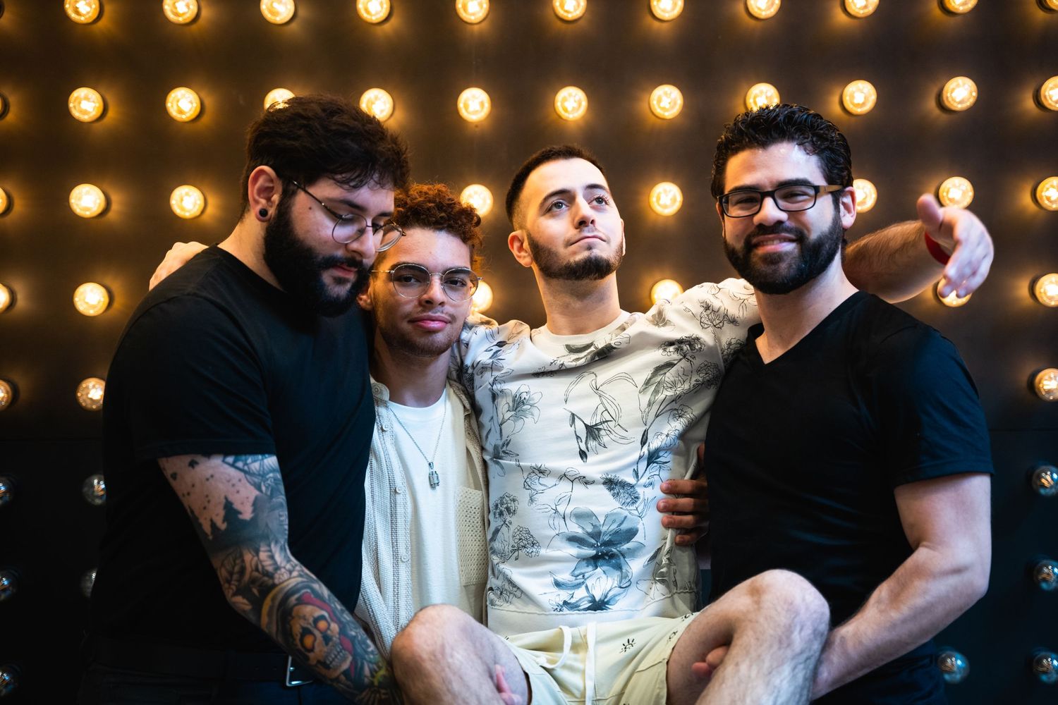 Four friends pose together against a backdrop of golden stage lights.