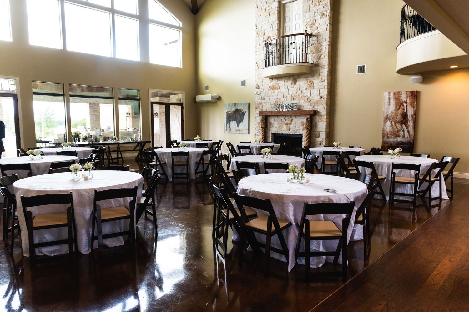Elegant reception hall with stone fireplace and round tables set for a wedding celebration.