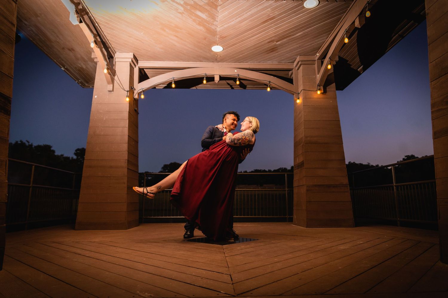 Dramatic dip dance pose silhouetted in a wooden gazebo at twilight.