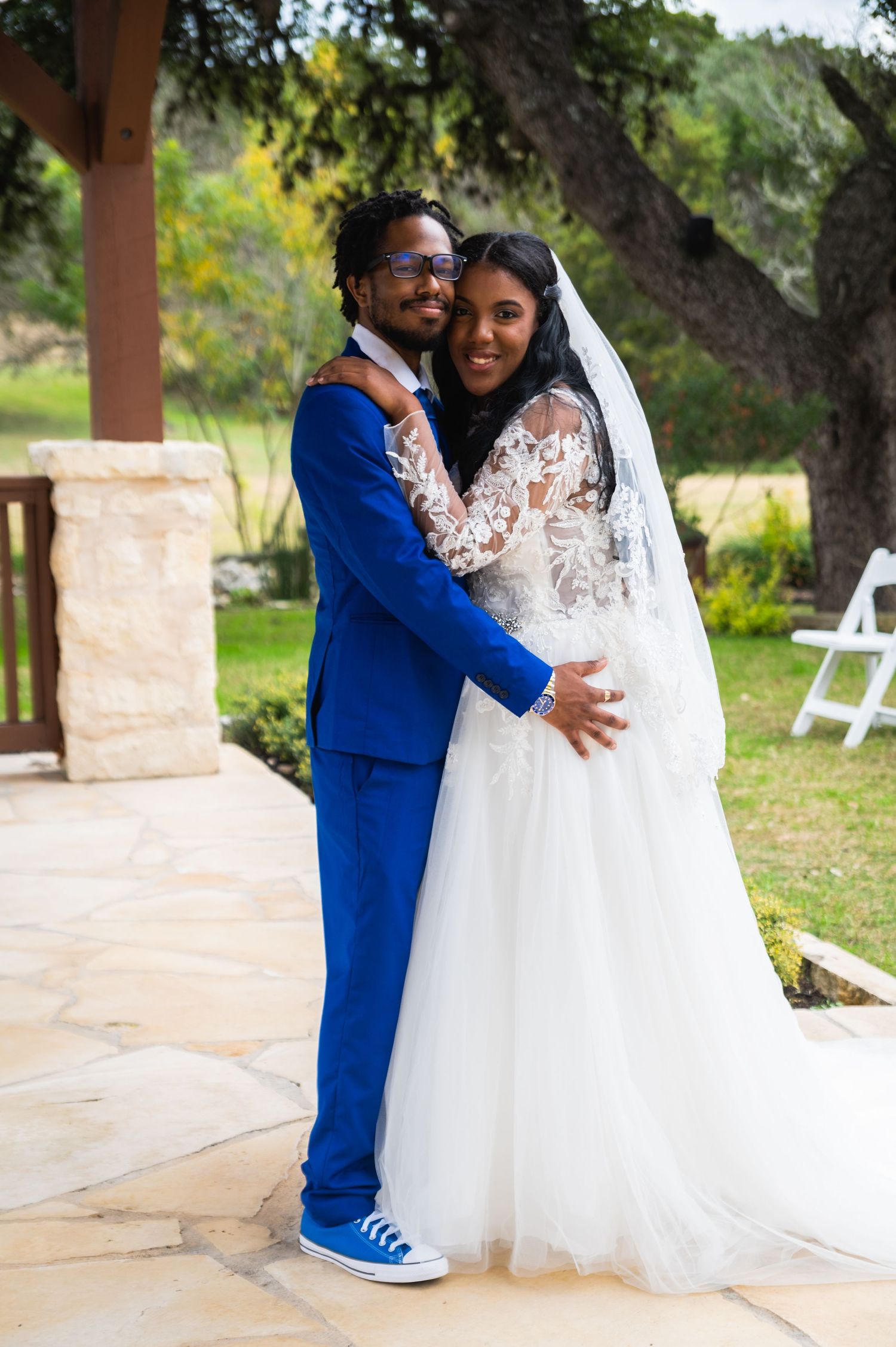 Newlyweds share a joyful moment together wearing a lace wedding gown and bright blue suit with sneakers.