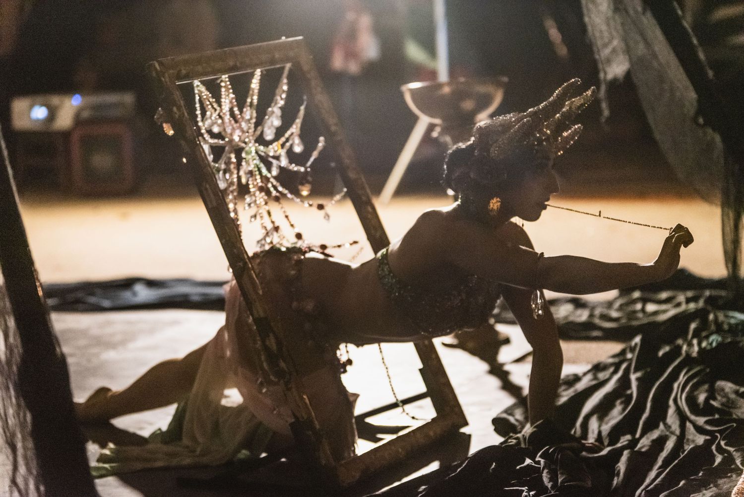 Silhouetted theatrical props and set pieces create dramatic shadows on a dimly lit stage.
