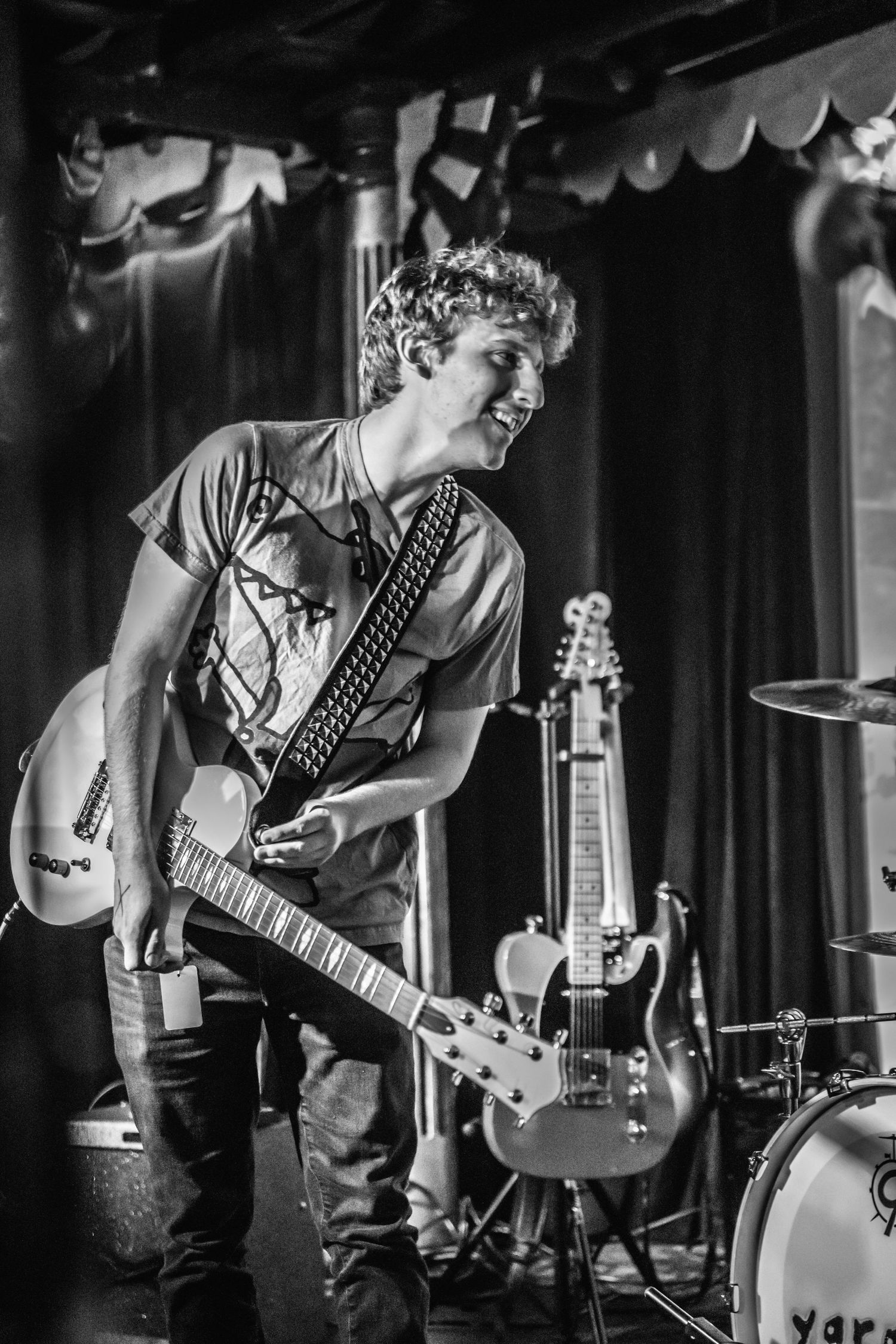 Black and white photo of musician playing electric guitar on stage.