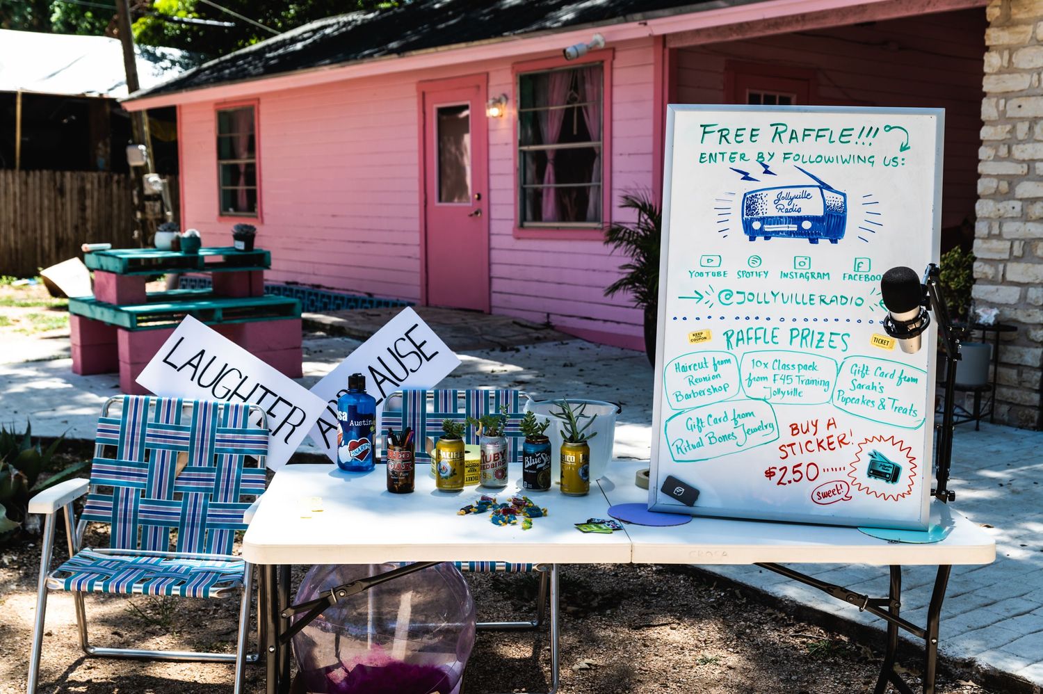 Pink building with outdoor vendor table displaying handmade products and price list.