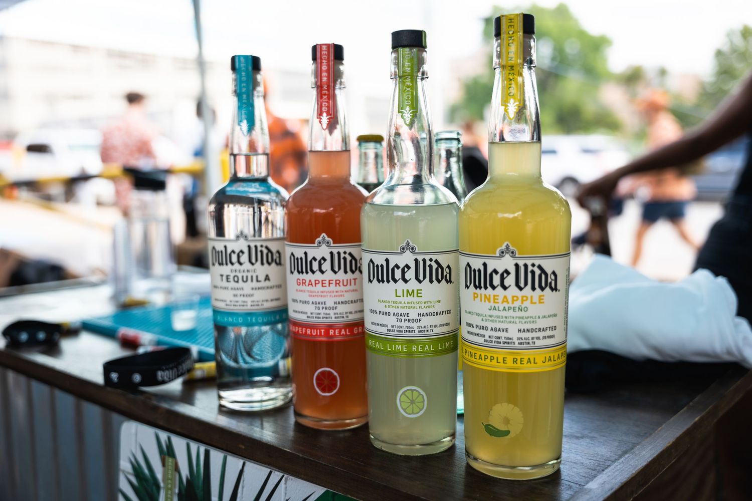 Row of colorful Dulce Vida tequila bottles displayed on an outdoor bar counter.