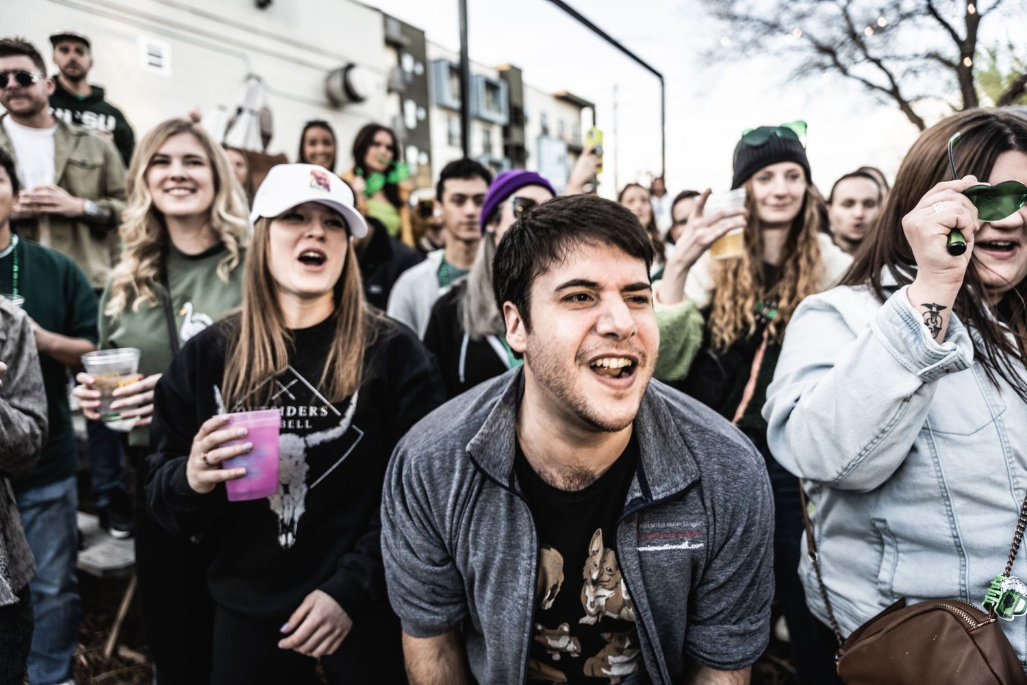 Energetic audience members laughing and cheering at an outdoor gathering.