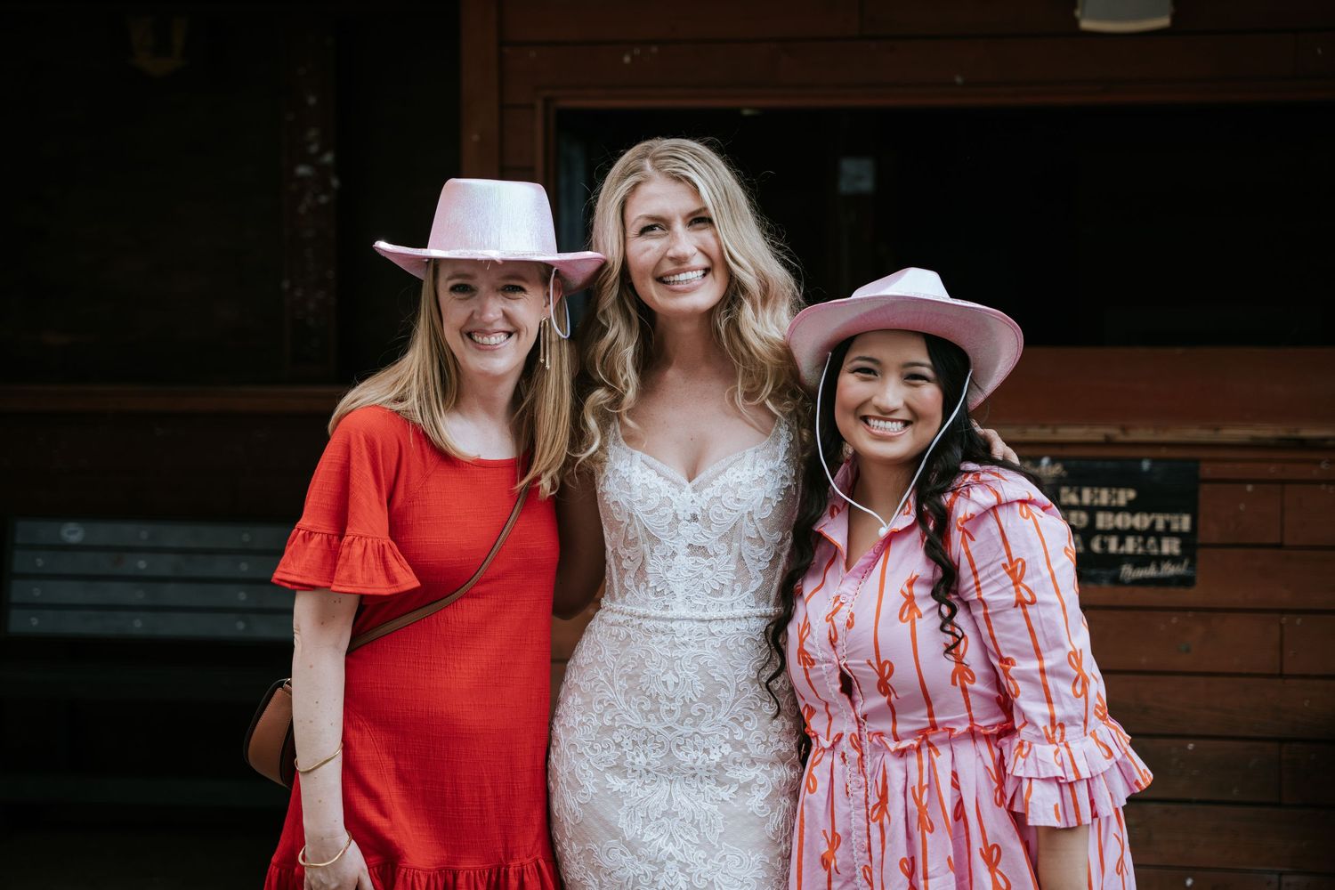 Group photo featuring pink cowboy hats and festive attire outside a rustic venue.
