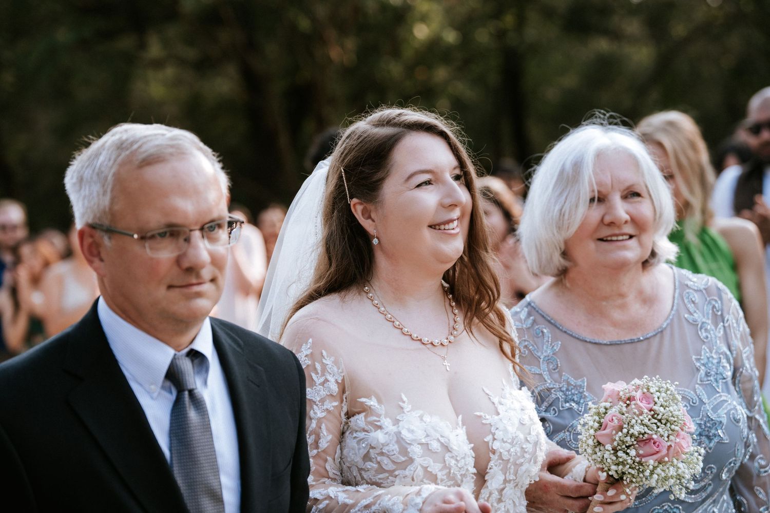 An emotional moment shared during a wedding processional on an outdoor walkway.