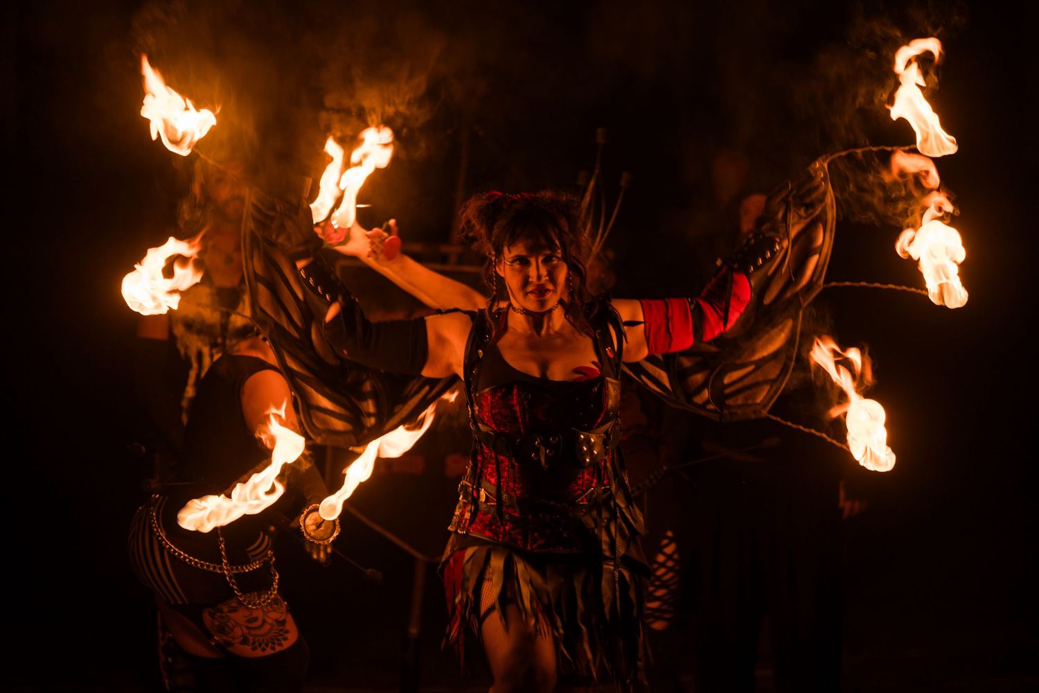 Dramatic fire performance with multiple flaming torches creating a spectacular night display.