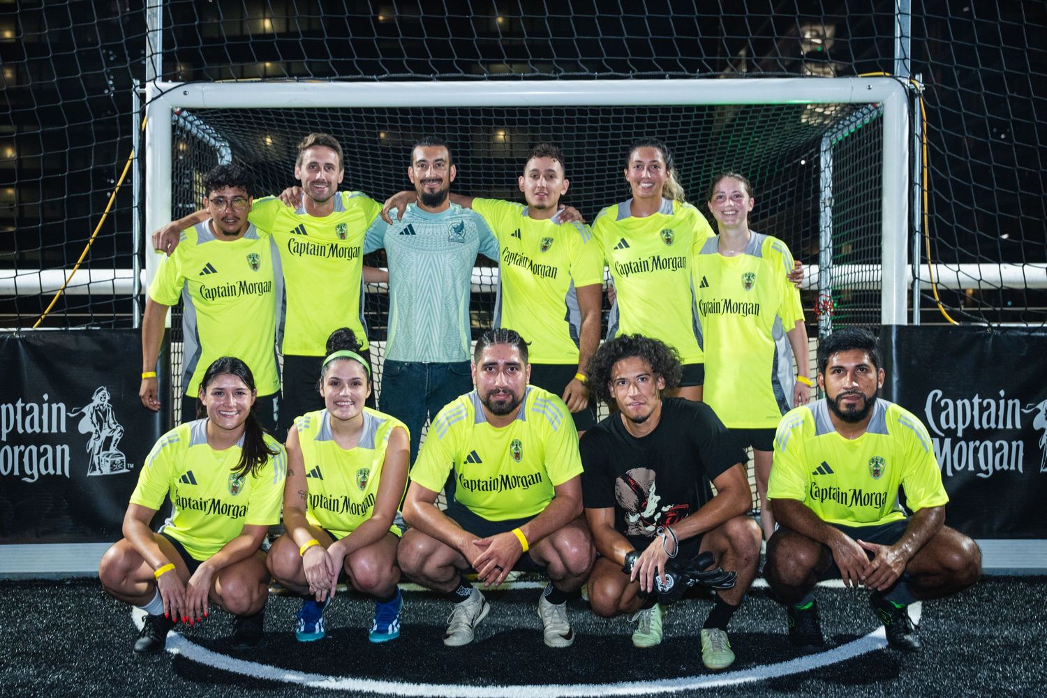 Soccer team in bright yellow jerseys poses together in front of goal post.