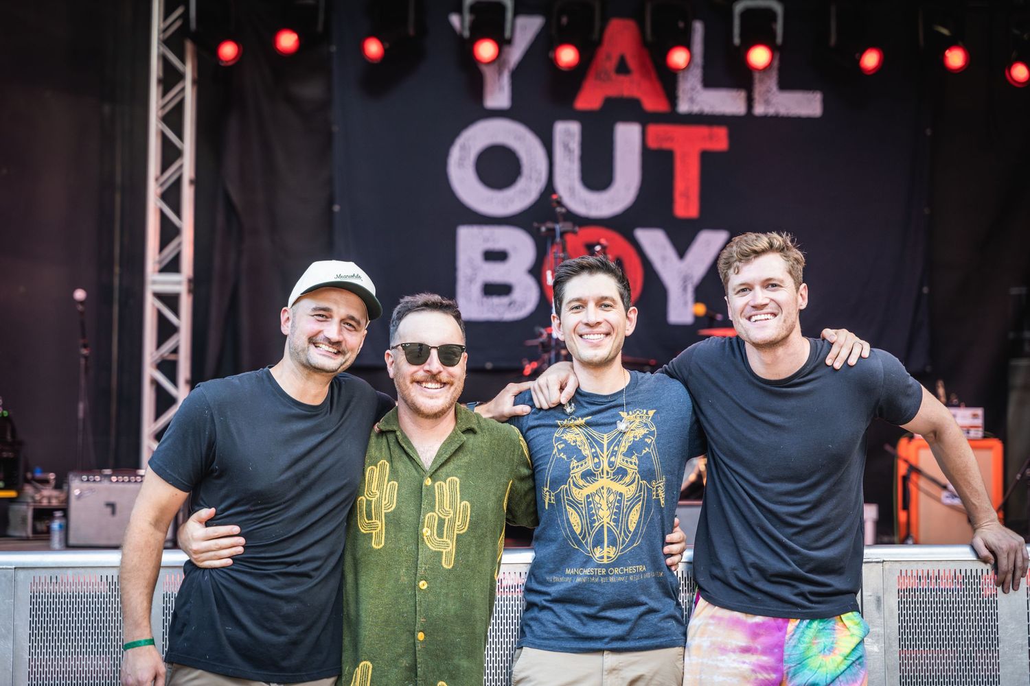 Band performing on stage with Tall Out Boy signage and red lighting effects.