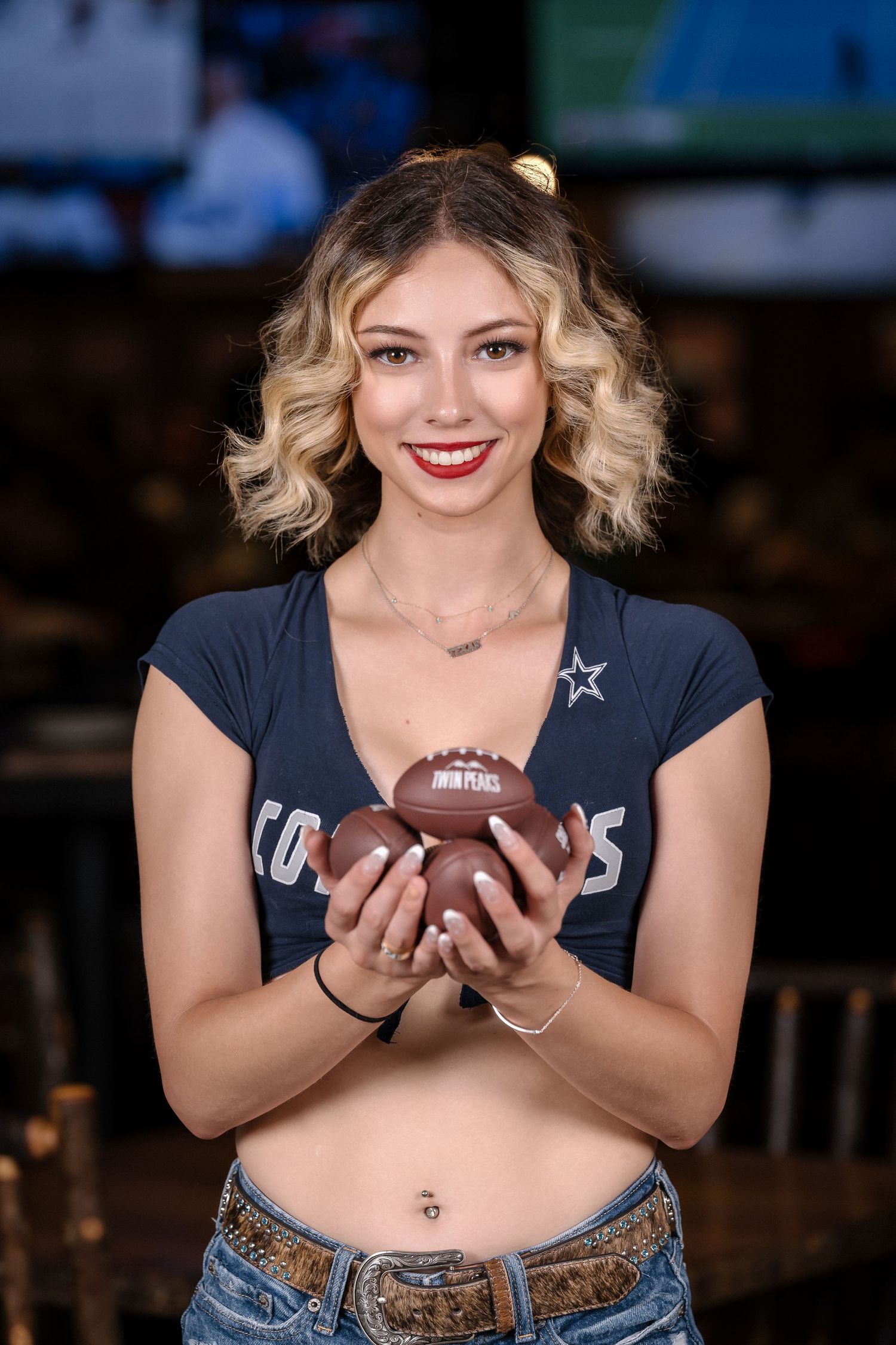 Sports bar server holding football with Dallas Cowboys themed outfit.